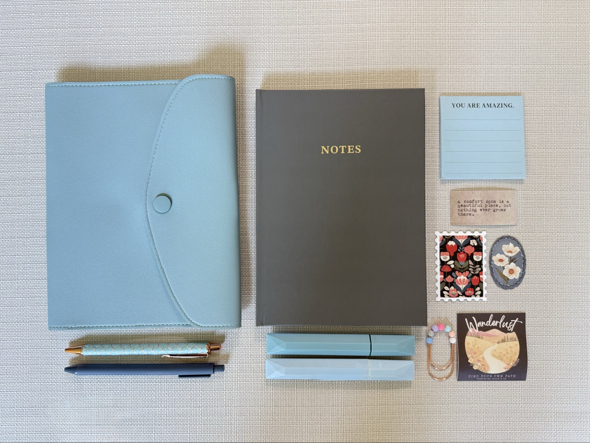 Blue snap folio journaling set arranged flat with notebook, sticky note pad, stickers and writing tools