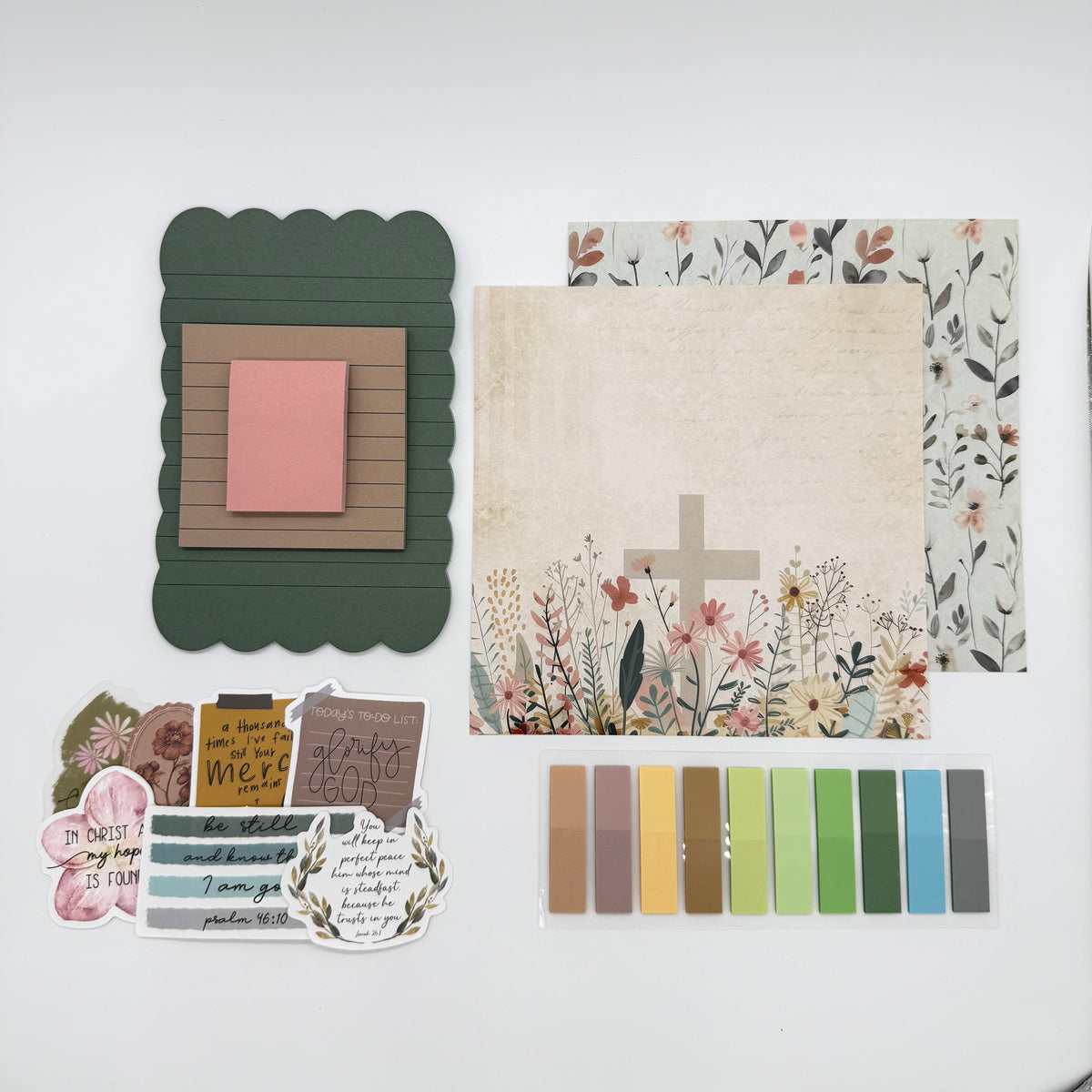 A flat-lay display of a scrapbook or card crafting kit featuring various paper elements, stickers, and a color palette strip on a white background.