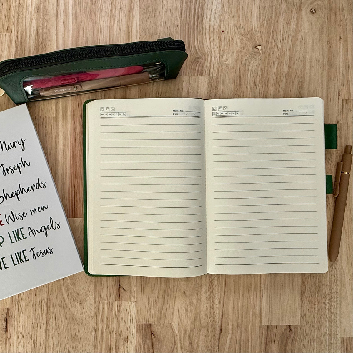 Evergreen journal open to lined pages, with a zip pouch and a Christmas companion journal. Companion journal designs vary