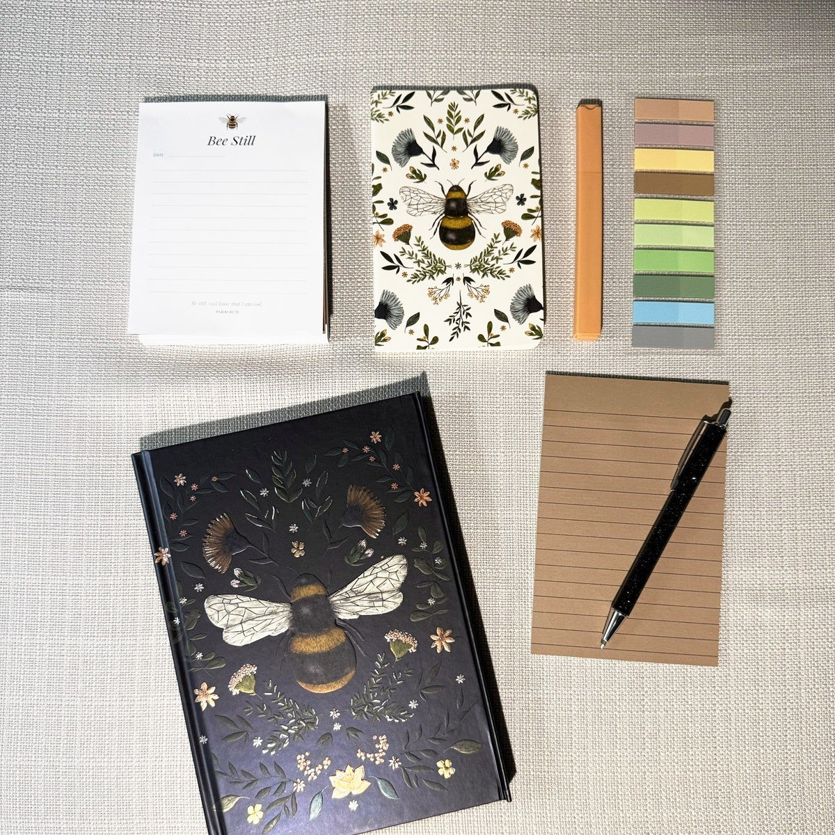 Bee Still notepad, mini bee notebook, black bee journal, page markers, sticky notes and pen from the Honey Bee Box; items vary.