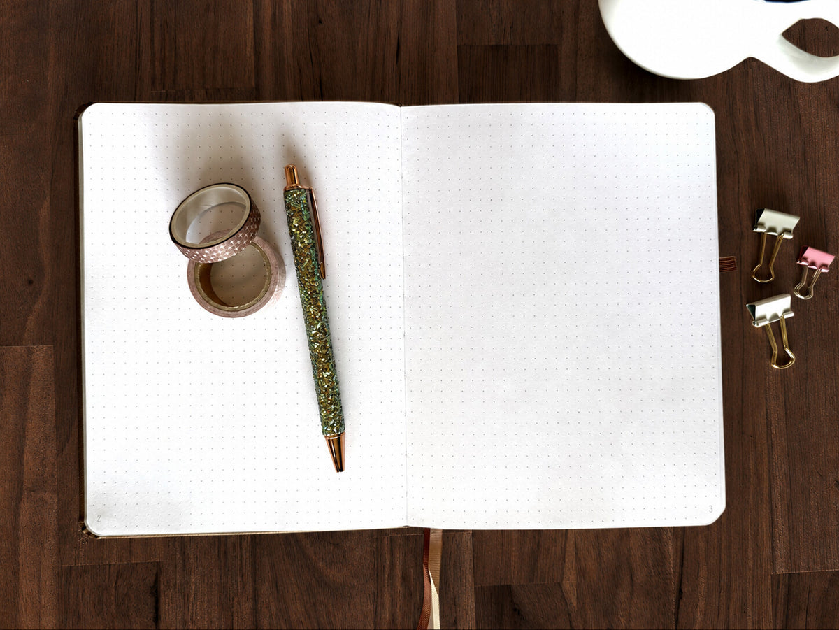 Open Cultivating Faith Deluxe Journal showing numbered dot grid pages and ribbon bookmarks on an espresso-brown tabletop; styling props not included