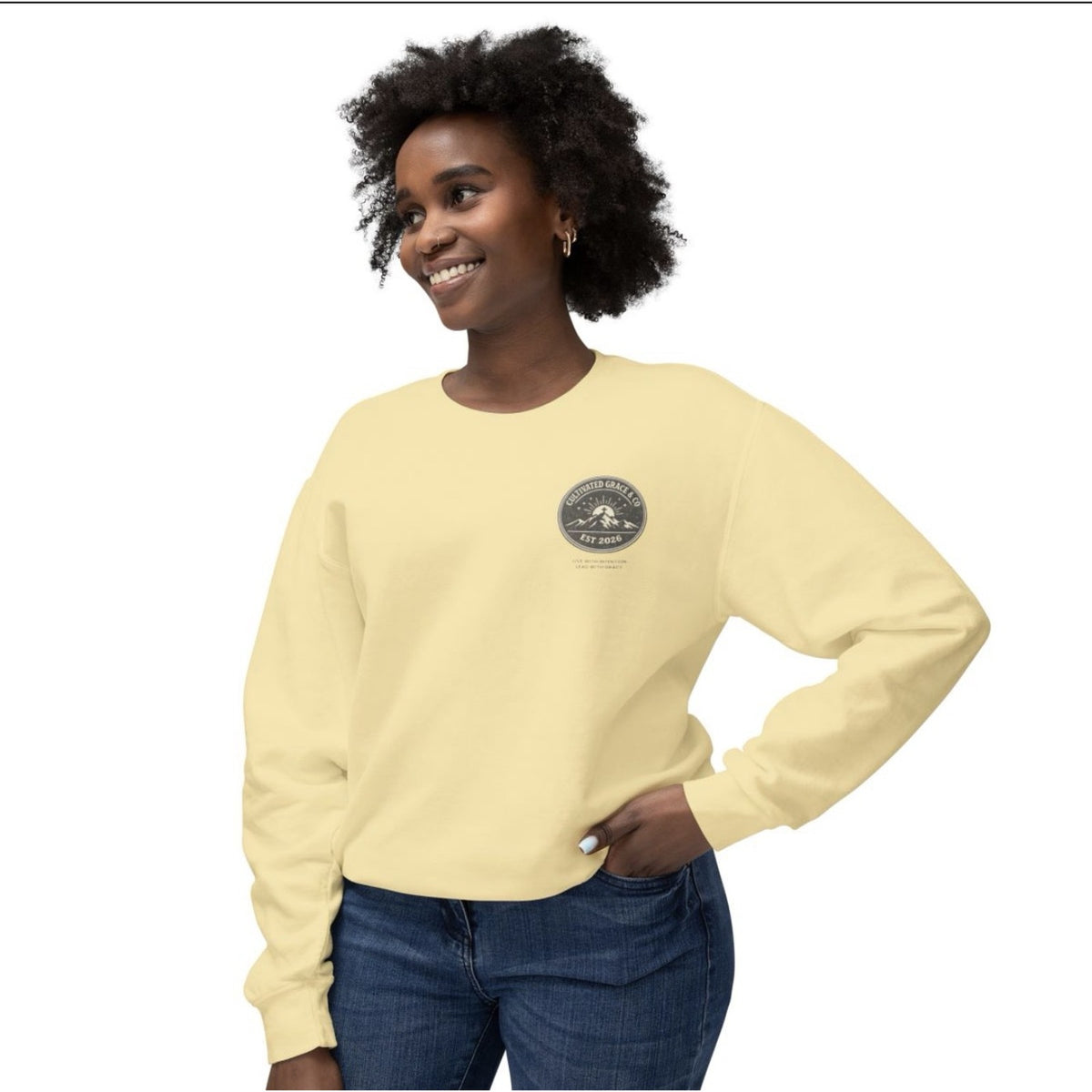 Cultivated Grace & Co. mountains and cross crewneck sweatshirt in Butter, worn, front view with left-chest badge