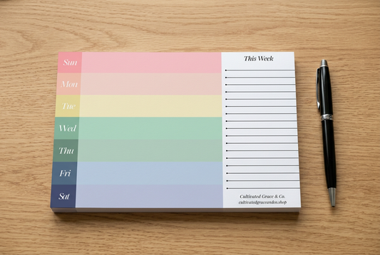 Weekly desk pad on a wood desk with a pen